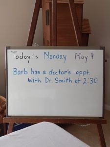 A whiteboard on a stand with the date and a note of an appointment written on it